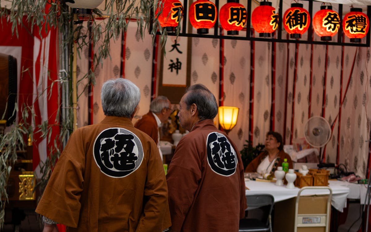 People in traditional attire at a vibrant Japanese street festival with lanterns