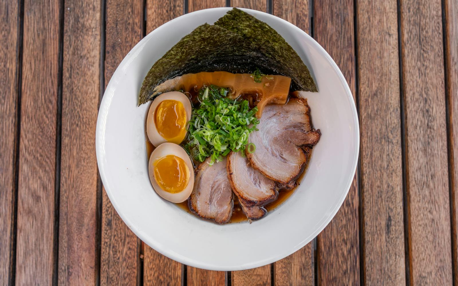 A bowl of Hakata-style tonkotsu ramen with chashu pork, soft-boiled egg, scallions and seaweed