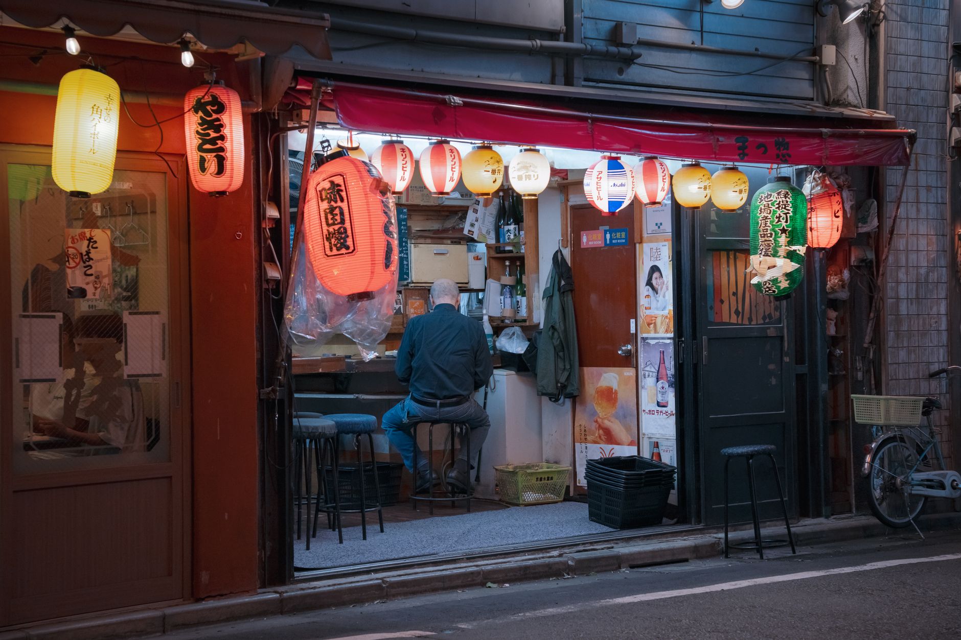 A Japanese izakaya street at night with lanterns and menus