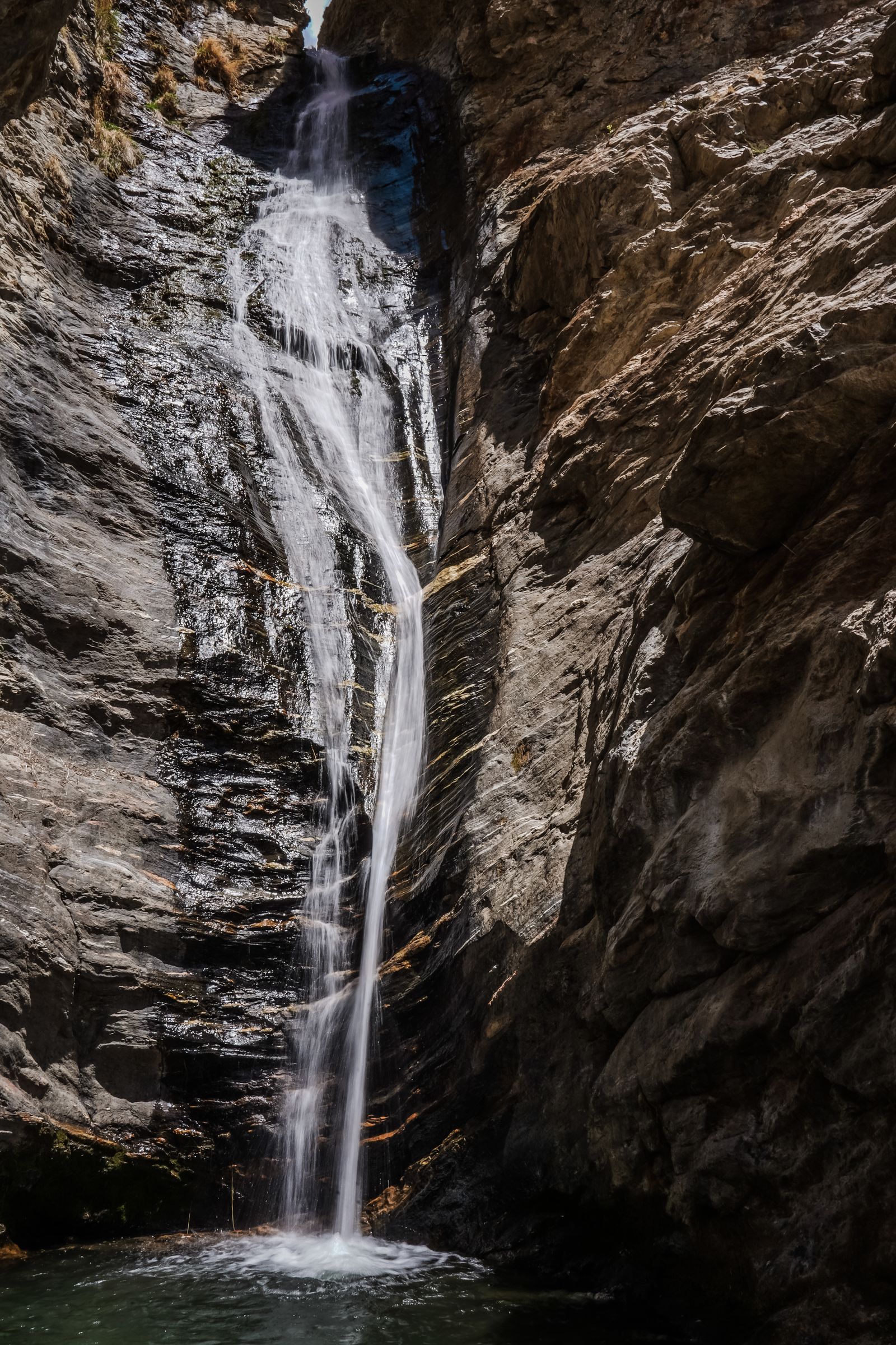 Tall thin waterfall dropping into the narrow emerald canyon of Takachiho Gorge