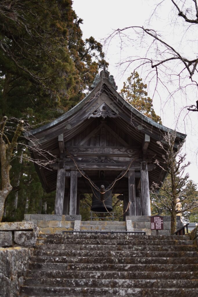 Stone staircase leading up to a mountain temple framed by autumn foliage in Japan