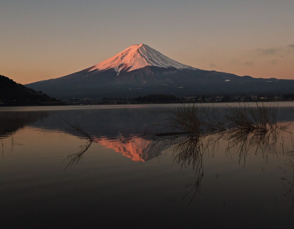 Snow-capped Mount Fuji reflected in the calm water of Lake Kawaguchiko