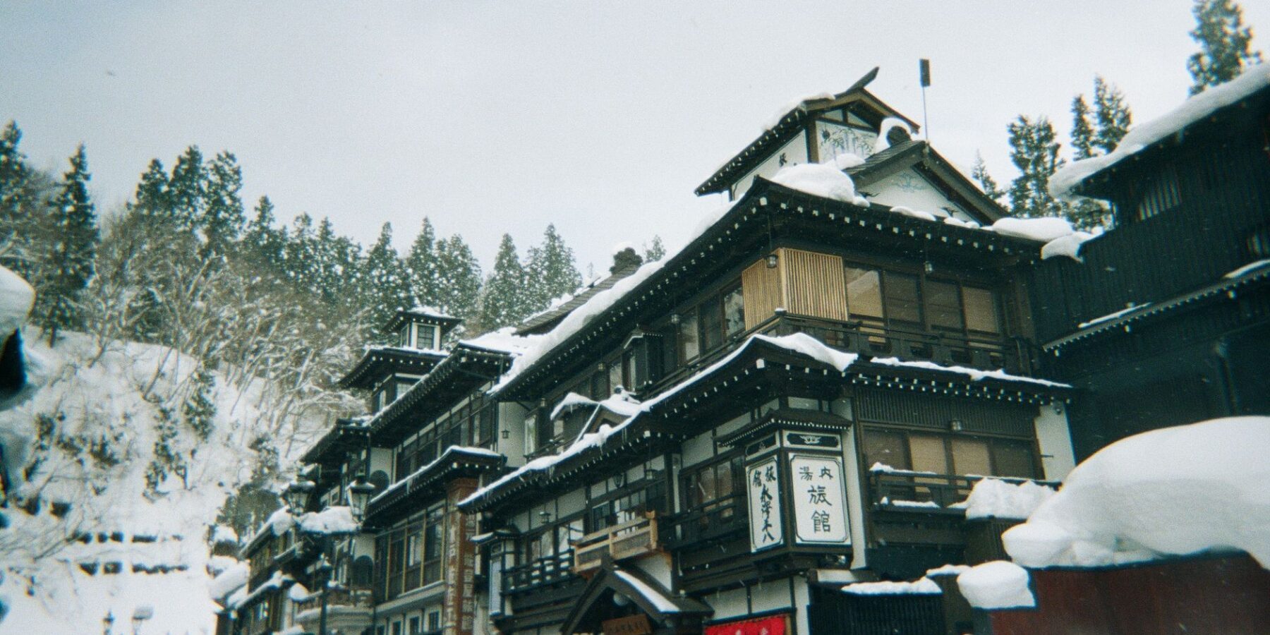 Snow-covered wooden ryokan lining the river in Ginzan Onsen, Yamagata