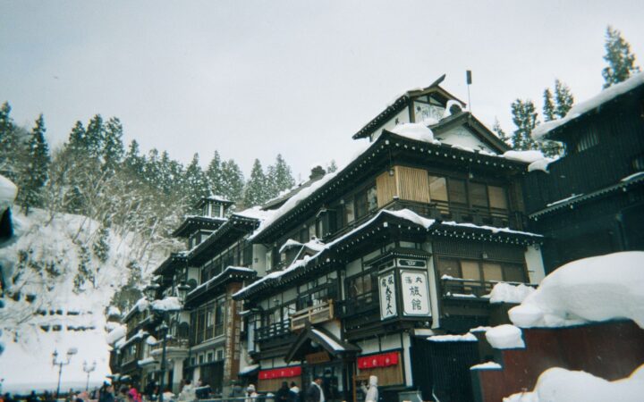 Snow-covered wooden ryokan lining the river in Ginzan Onsen, Yamagata