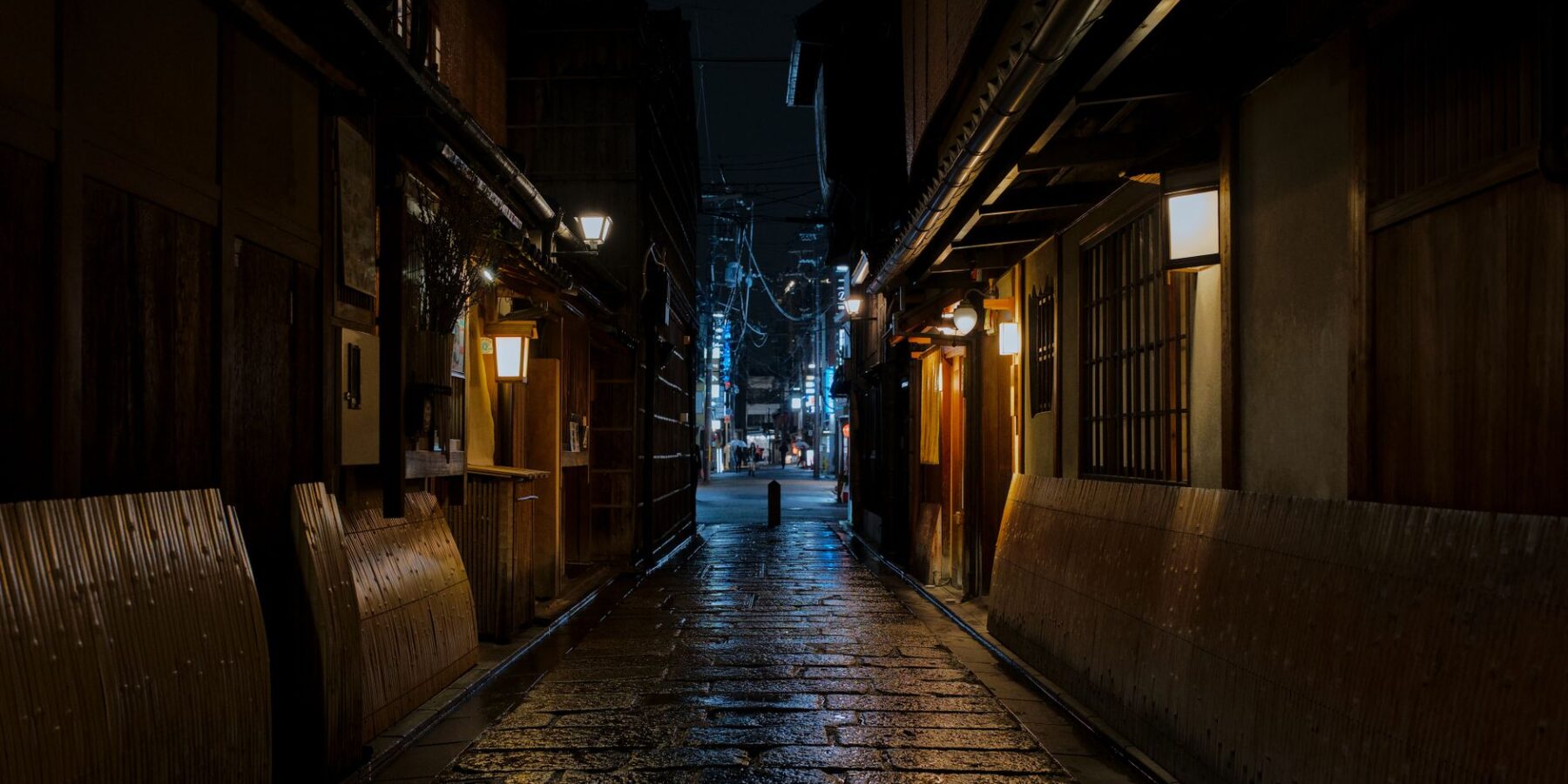 Lantern-lit stone alley with wooden machiya at night in Gion, Kyoto