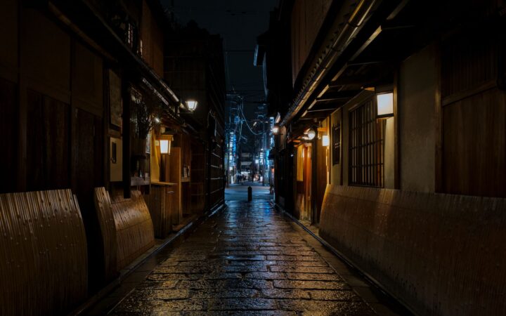 Lantern-lit stone alley with wooden machiya at night in Gion, Kyoto