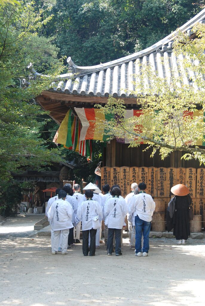 Pilgrims in white robes reciting the Heart Sutra in front of a temple hall