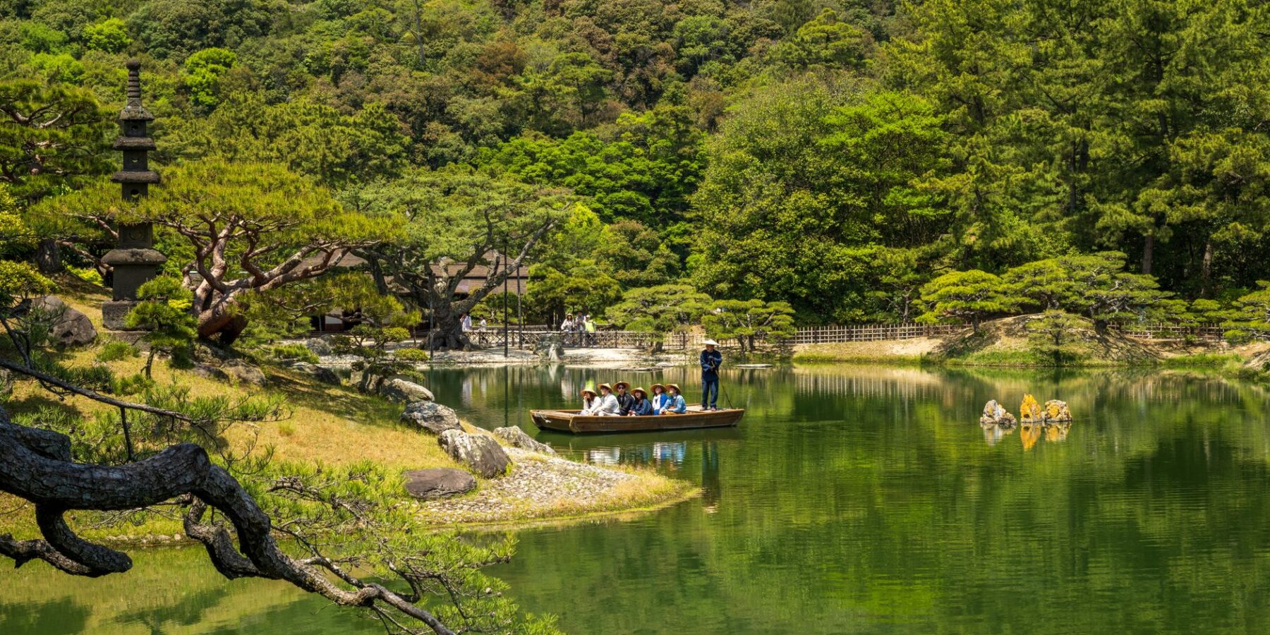 Visitors on a traditional boat ride on the pond of Ritsurin Garden, Takamatsu, Kagawa