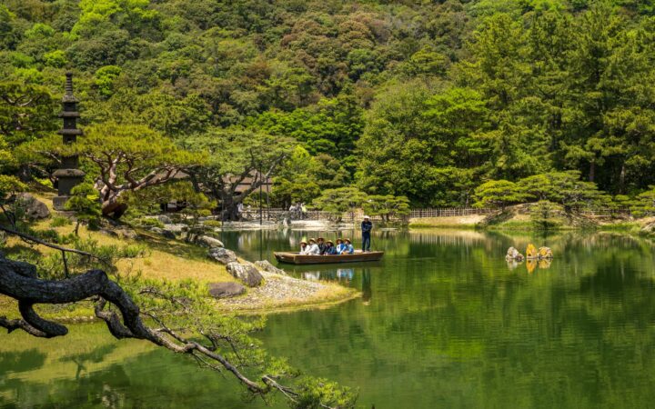 Visitors on a traditional boat ride on the pond of Ritsurin Garden, Takamatsu, Kagawa