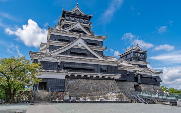 Kumamoto Castle keep and stone walls under a blue sky in Kumamoto, Japan