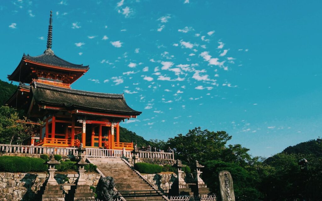 The vermilion gate and pagoda of Kiyomizu-dera Temple in Kyoto under a blue sky