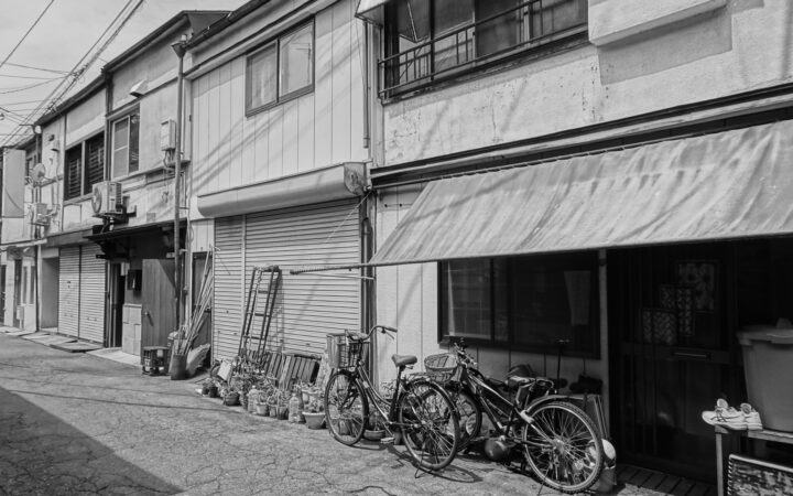 Black-and-white view of bicycles outside old shopfronts on a street in Morioka, Iwate