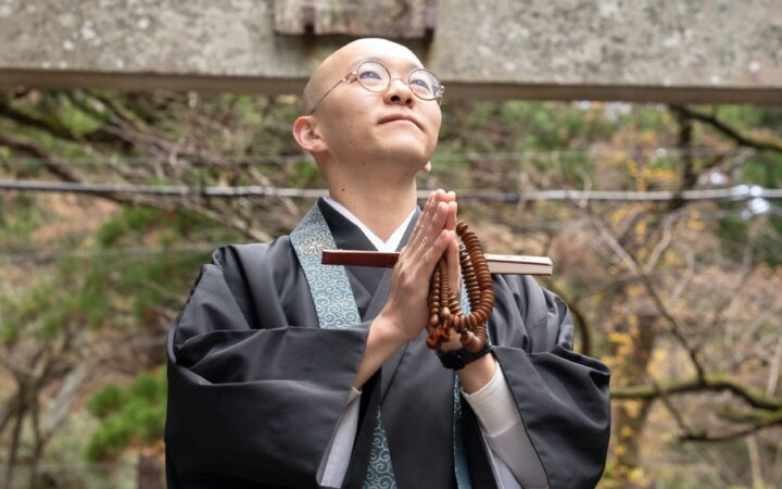 A Buddhist monk praying at a moss-covered torii gate on Mount Daisen, Tottori