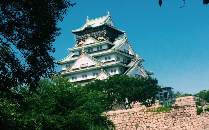 Osaka Castle main keep above stone walls and trees under a blue sky, Osaka, Japan