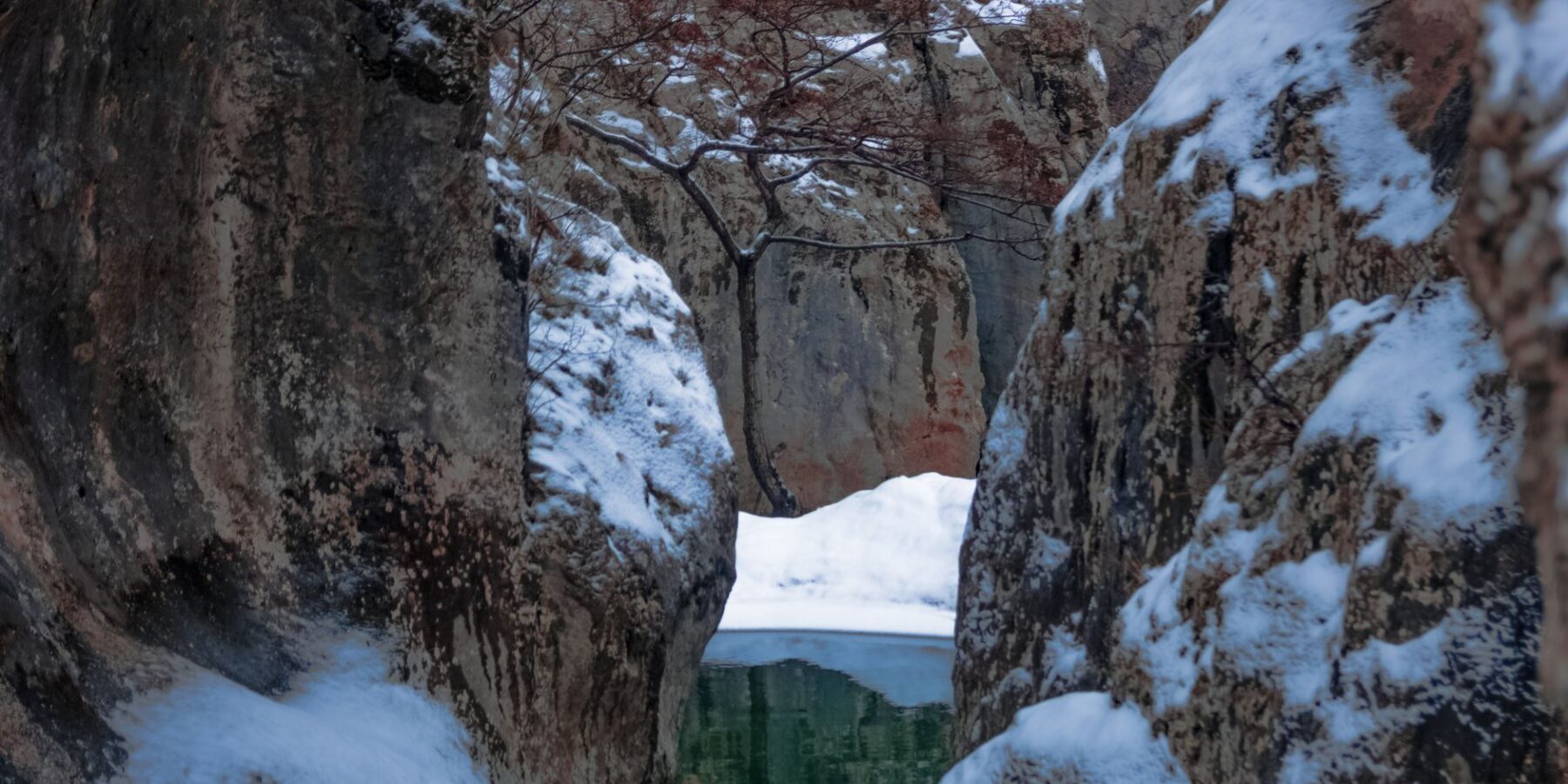 Snow-dusted rock walls of a narrow river gorge in Japan